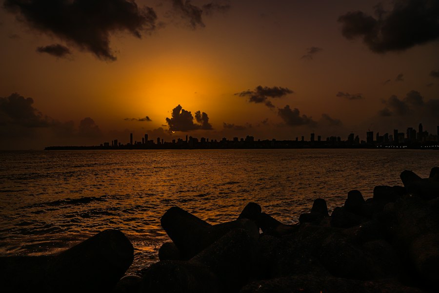 An orange sunset over a sea wall